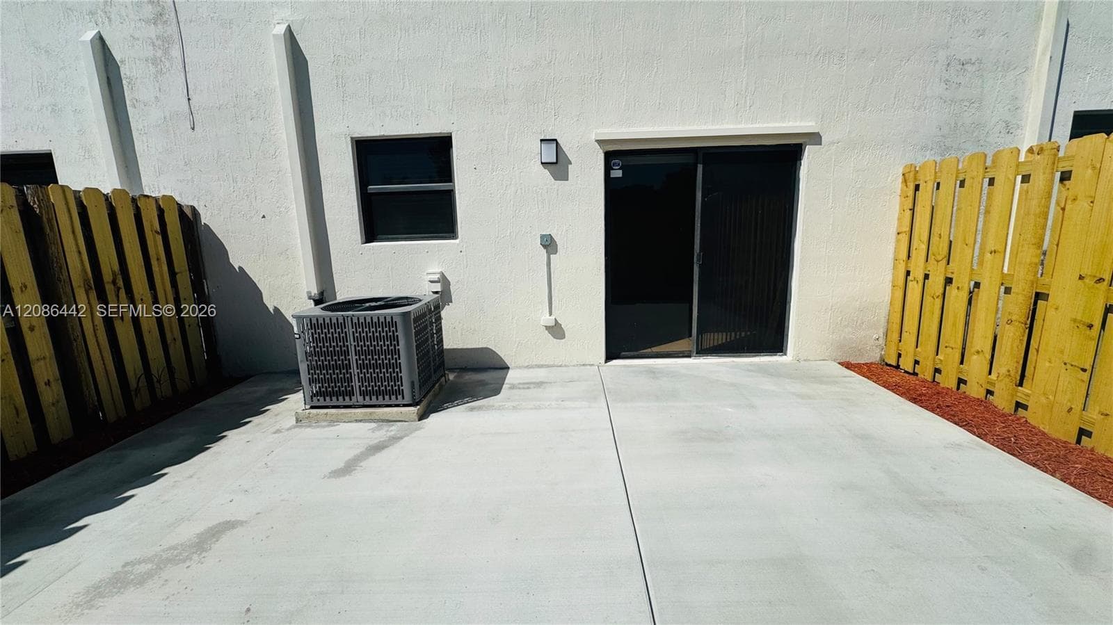Concrete patio featuring a sliding glass door and fenced enclosure
