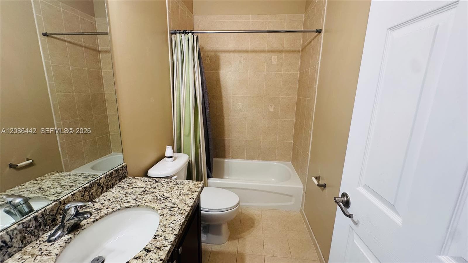 Bathroom featuring a stone-patterned countertop, vanity with an integrated oval sink, full-length vanity mirror, tile shower surround, and a tub-shower combination