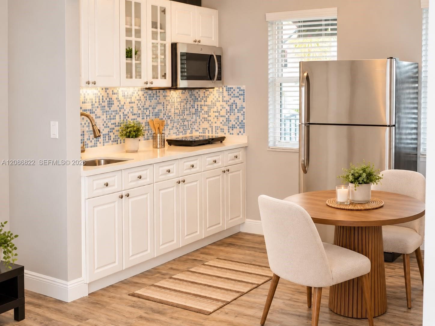 Kitchen featuring white shaker-style cabinetry, mosaic tile backsplash, solid-surface countertops, stainless steel appliances, and wood-finish flooring