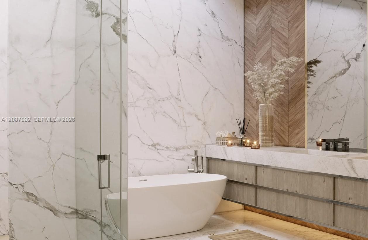 Freestanding soaking tub with a floor-mounted faucet, wall-to-wall stone-finish surfacing, floating wood-finish vanity, and herringbone wood-patterned accent wall
