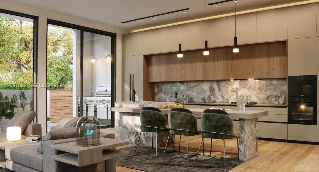 Modern kitchen featuring flat-panel cabinetry, stone-surfaced waterfall island, natural stone backsplash, integrated double wall ovens, and wood-finish flooring