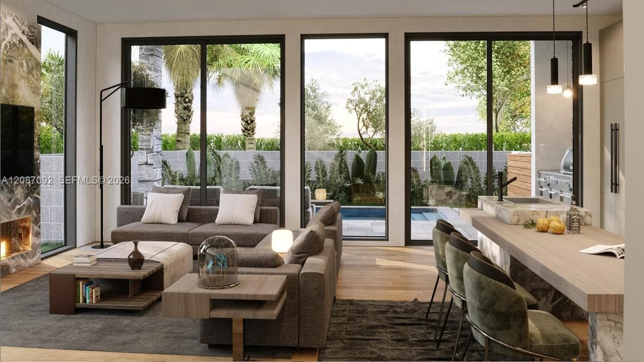 Open-concept interior featuring floor-to-ceiling glass sliding doors, stone-clad fireplace surround, wood-finish flooring, and built-in kitchen island with stone waterfall edge