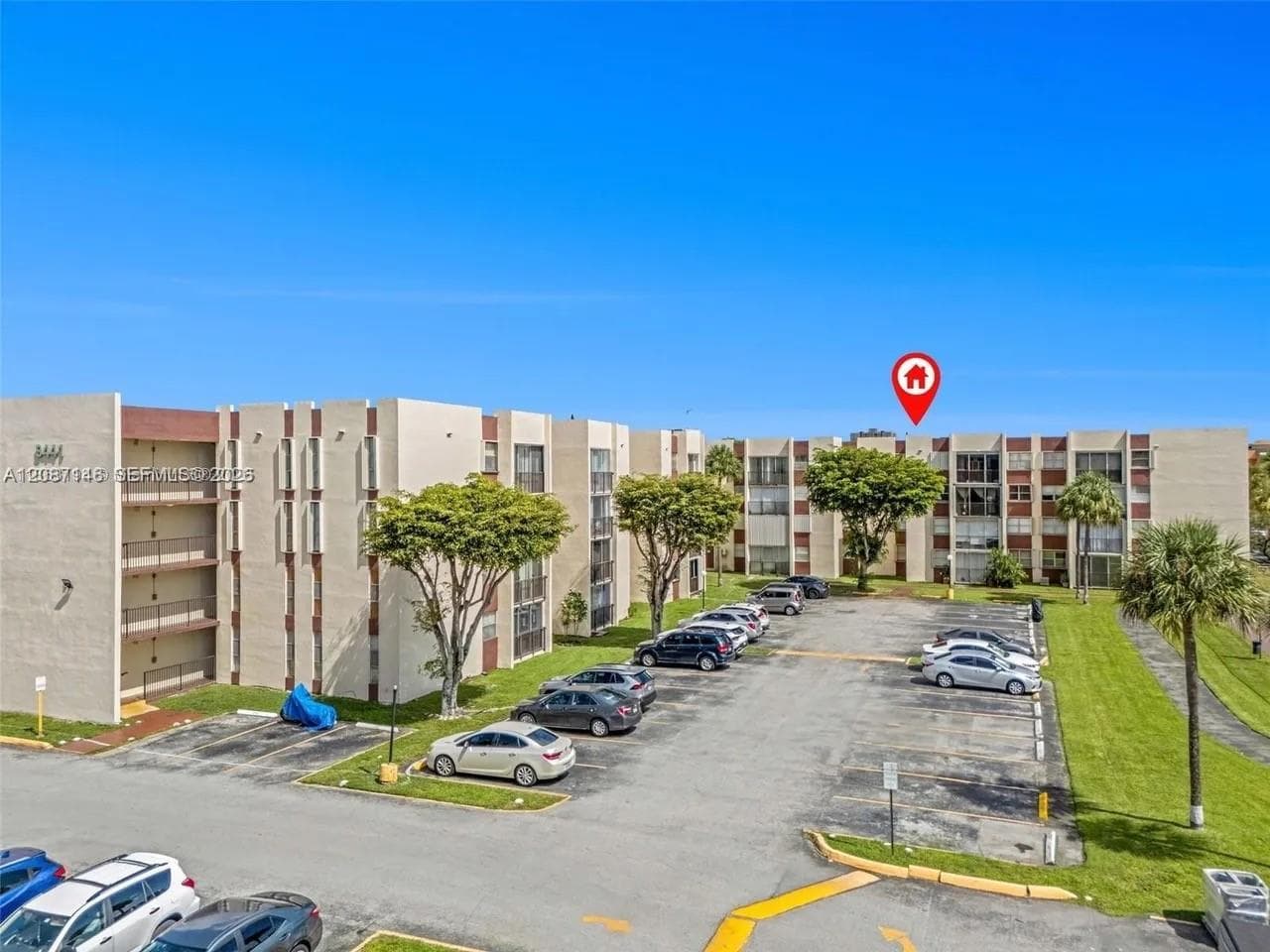 Multi-story concrete building with stucco finish, integrated balconies, and designated surface parking area