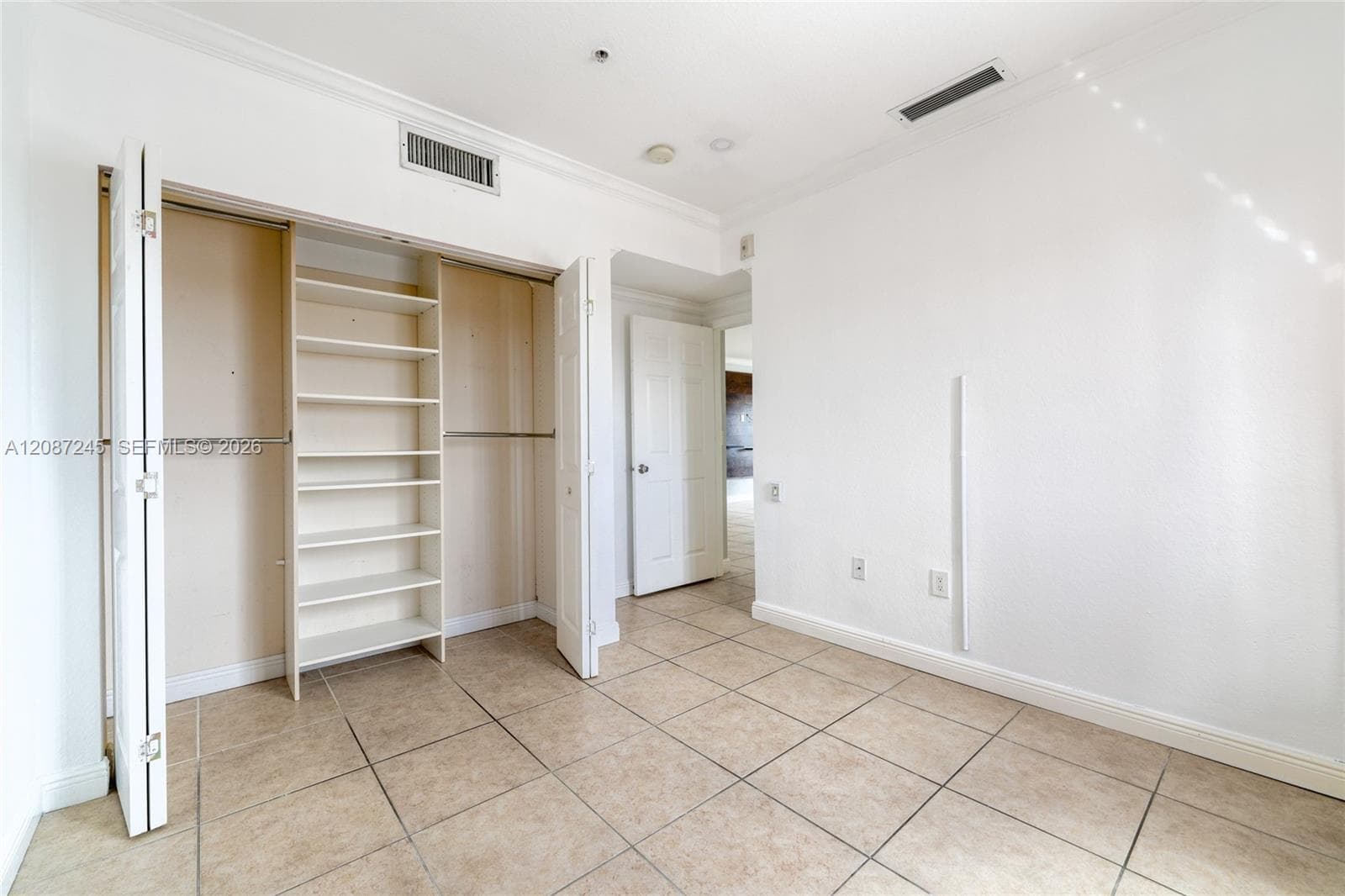 Neutral-toned tile flooring, built-in closet shelving, dual closet rods, and solid-core interior doors