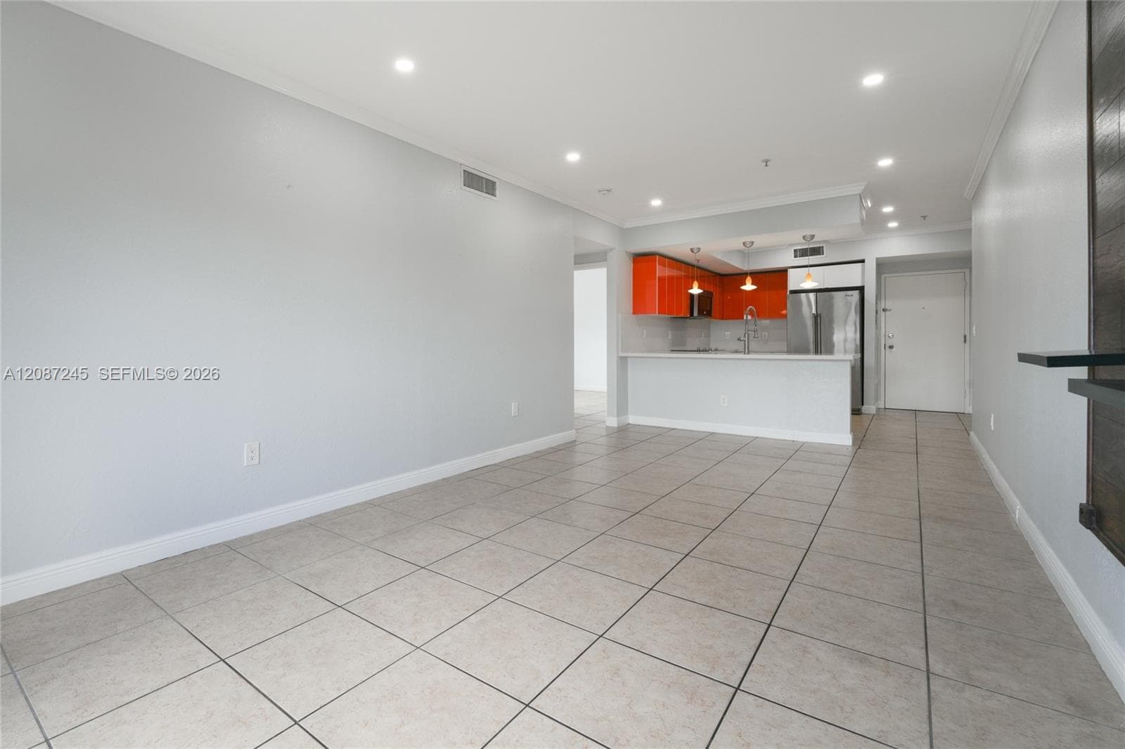Open-concept interior featuring large-format tile flooring, high-gloss orange cabinetry, stone-finish countertops, stainless steel appliances, and recessed lighting