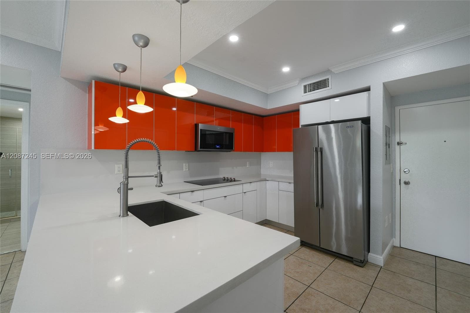 Kitchen featuring glossy orange upper cabinetry, white flat-panel lower cabinets, quartz countertops, stainless steel appliances, and a single-basin undermount sink with a high-arc pull-down faucet