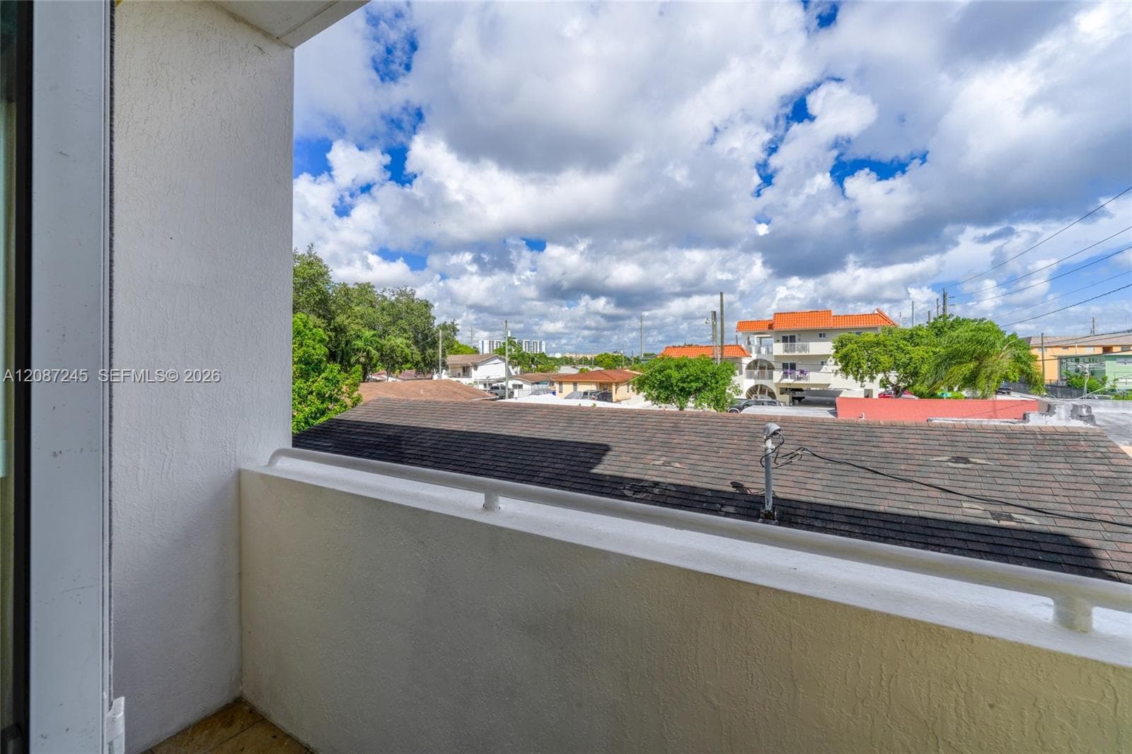 Covered balcony featuring white stucco walls and a horizontal metal railing