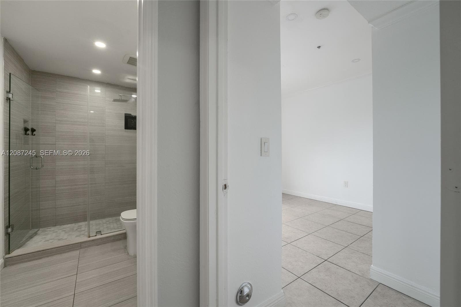 Walk-in glass-enclosed shower featuring horizontal stone-finish wall tile, recessed lighting, and stone-finish floor tile