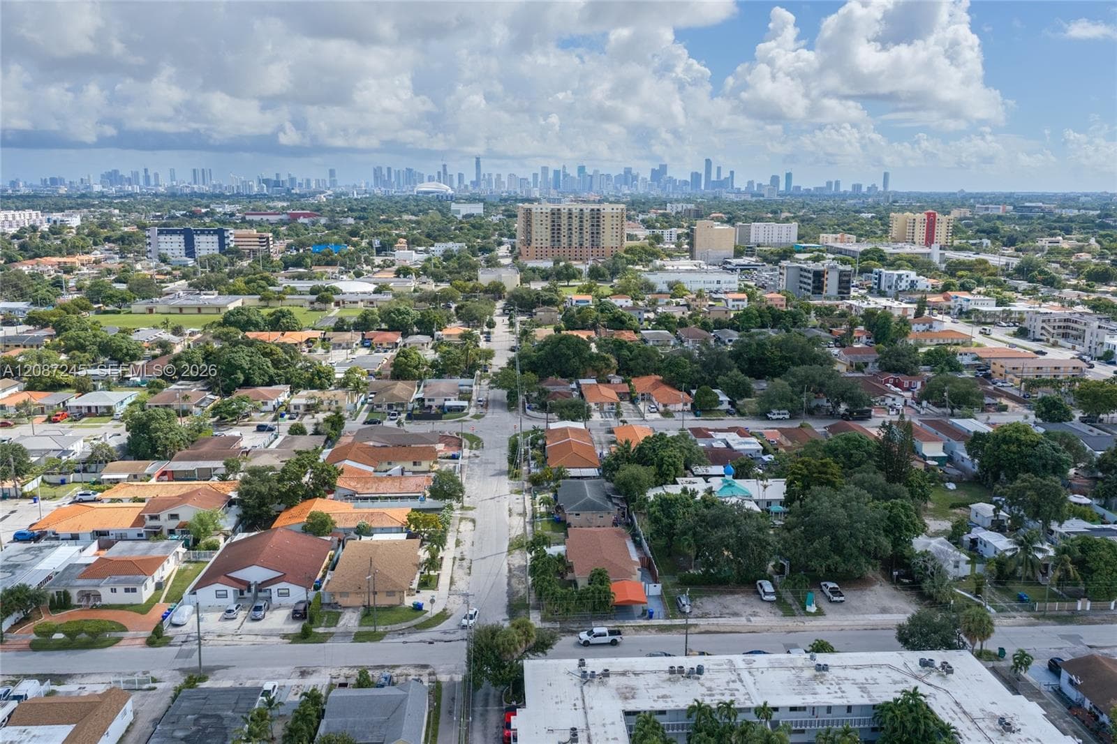 Aerial perspective featuring an established suburban neighborhood with paved streets and mature tree canopies