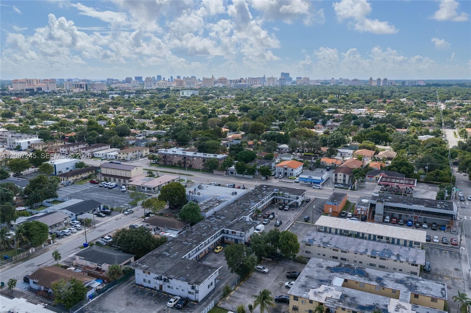 Aerial perspective of a multi-unit residential property featuring paved on-site parking and mature landscaping