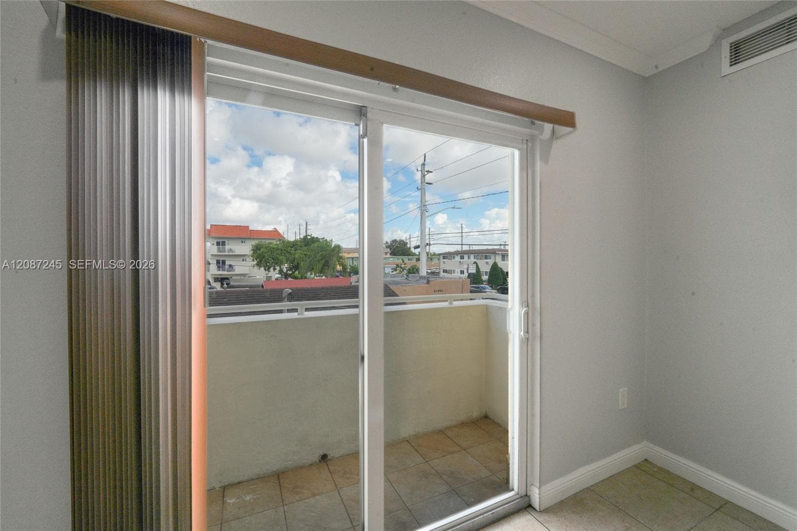 Sliding glass door opening to a private balcony featuring tiled flooring and a metal railing