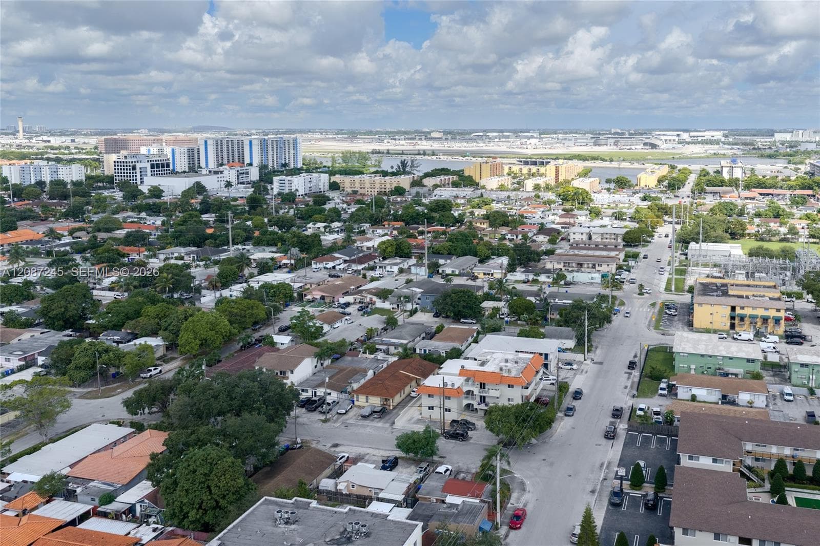 Aerial perspective of a dense urban environment featuring multi-story residential buildings, paved street networks, and mature canopy trees
