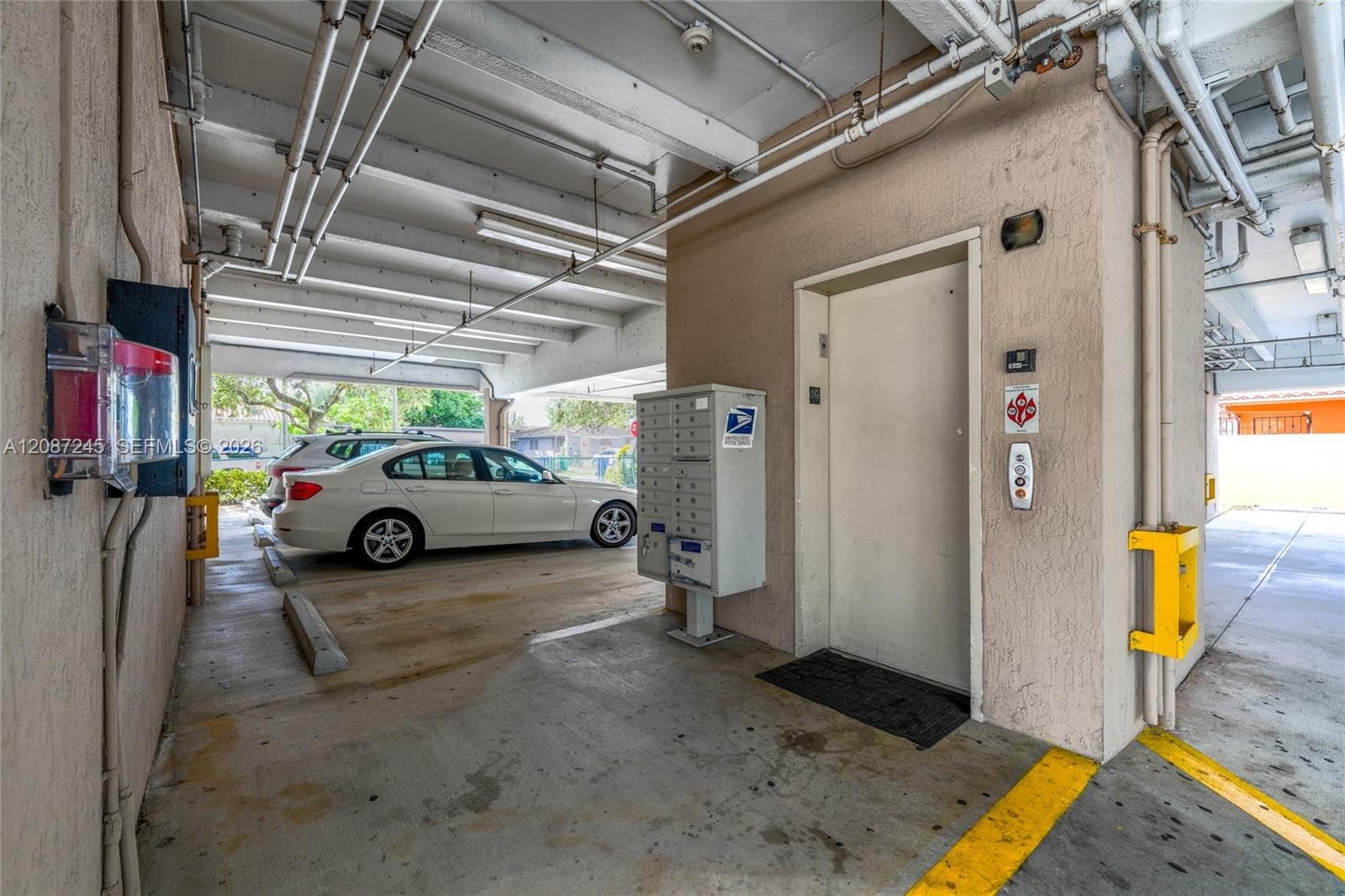 Covered parking area featuring a centralized elevator entrance and built-in communal mailboxes