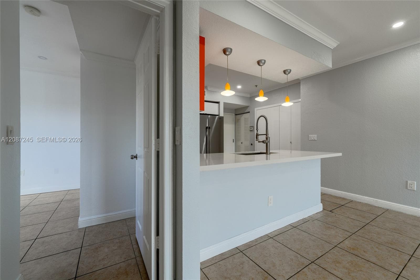 Kitchen featuring a peninsula with a stone-finish countertop, undermount sink, gooseneck faucet, three pendant light fixtures, and stainless steel appliances