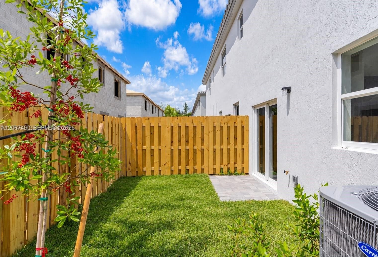 Private backyard featuring a wood privacy fence, paved patio, and manicured lawn