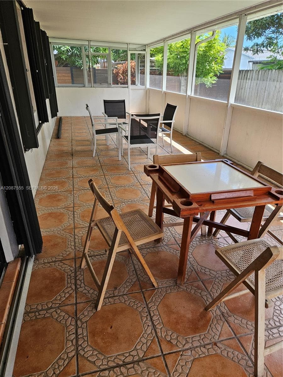 Enclosed patio featuring screened walls, a solid ceiling, and decorative ceramic tile flooring