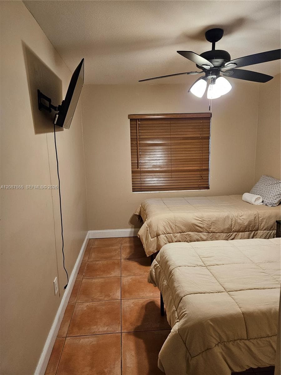 Ceramic tile flooring, ceiling fan with integrated lighting, wall-mounted television bracket, and horizontal window blinds