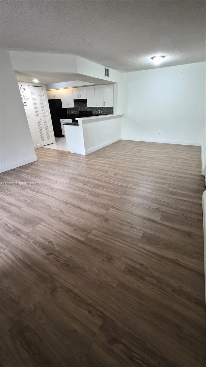 Open-concept interior featuring wood-finish flooring, white cabinetry, a breakfast bar, and recessed lighting