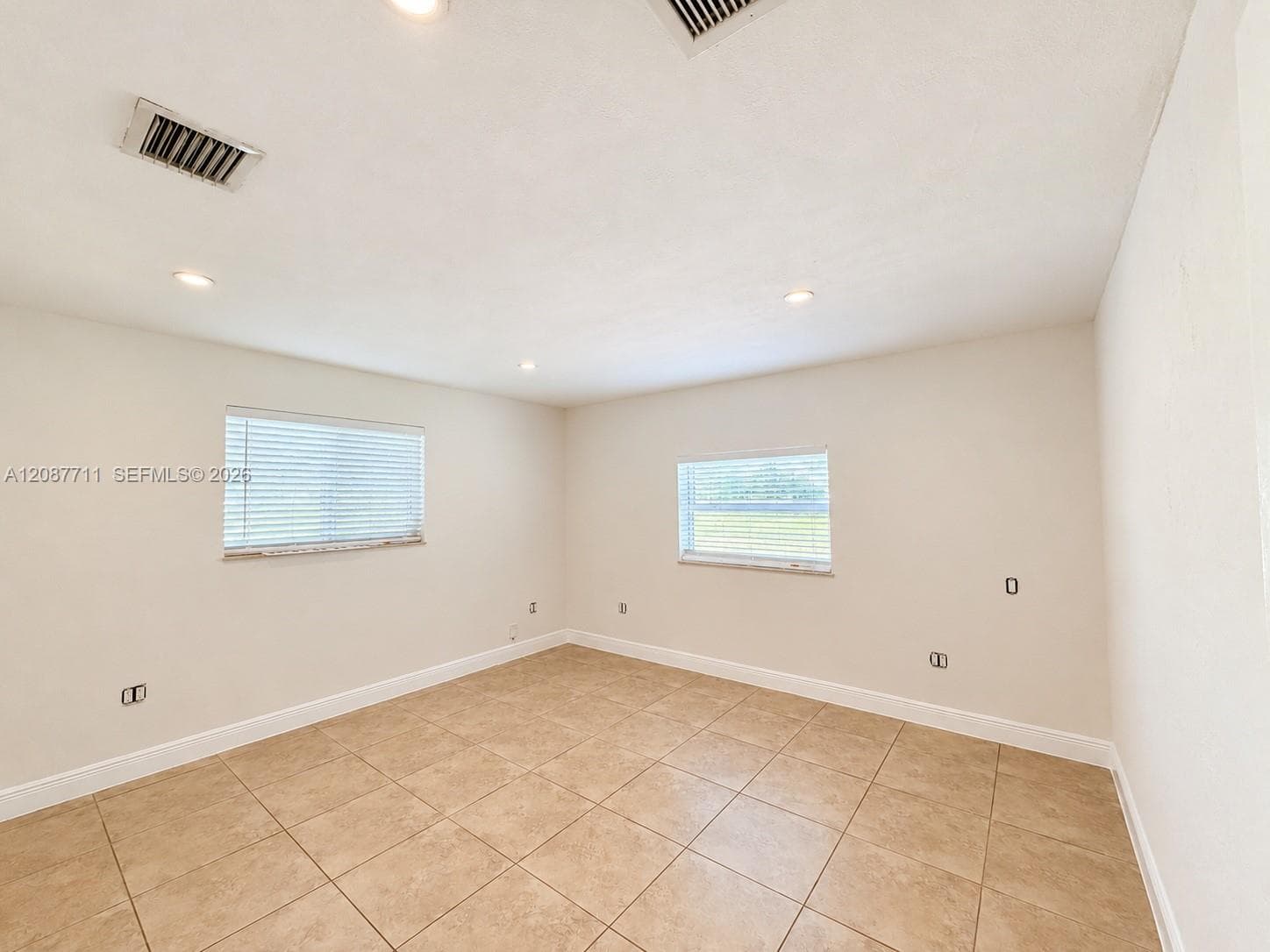 Neutral-toned tile flooring, recessed ceiling lighting, and dual windows with horizontal blinds