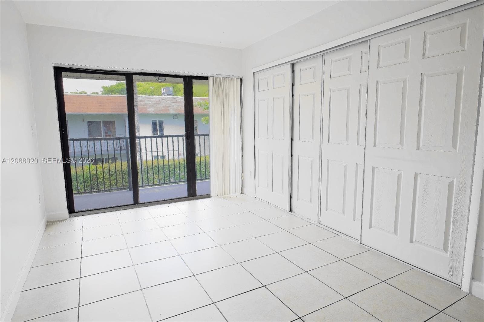 Bedroom with open balcony and wall-to-wall closet space.