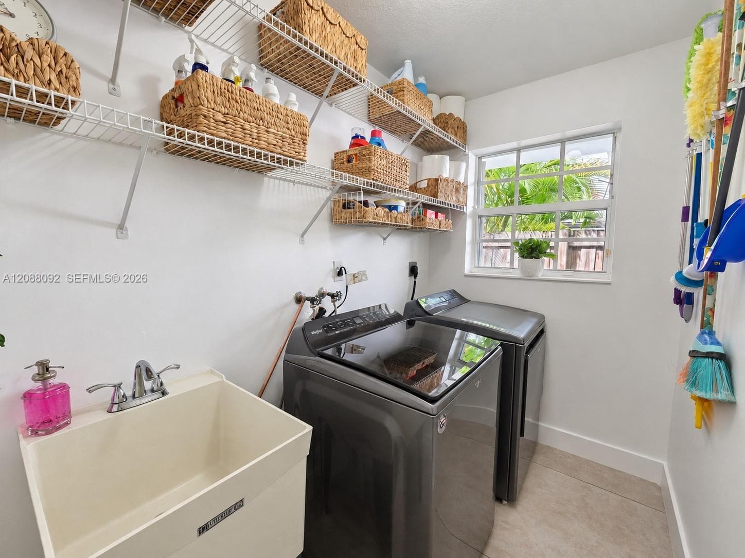 Spacious Laundry room with utility tub, sheves for storage, washer and dryer with  lots of natural light.