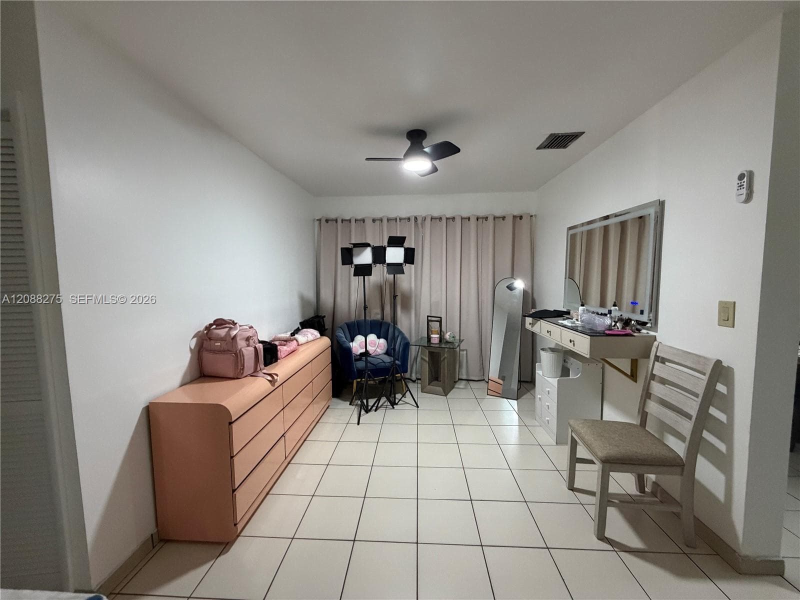Interior room featuring neutral ceramic tile flooring, a wall-mounted floating vanity with an integrated mirror, and a ceiling fan with light fixture