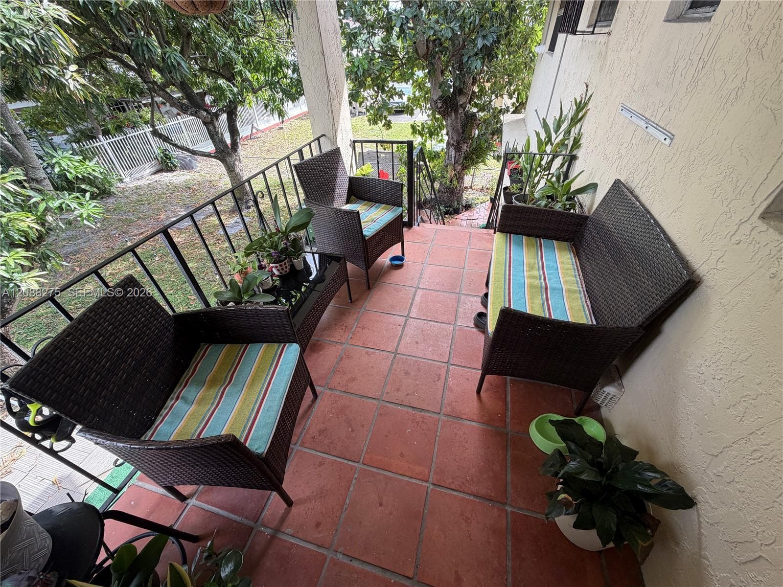 Covered balcony featuring terracotta-style tile flooring and a black metal railing