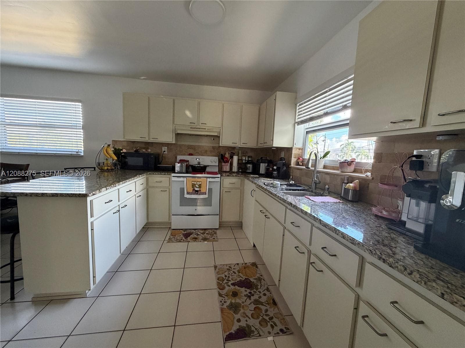 Kitchen featuring stone-finish countertops, tile flooring, light-toned cabinetry, and an integrated breakfast bar