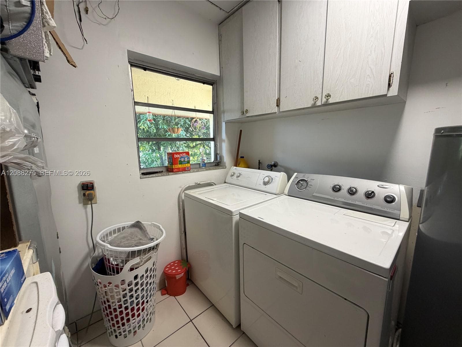 Laundry area featuring wall-mounted cabinetry, tile flooring, and a window with exterior exposure