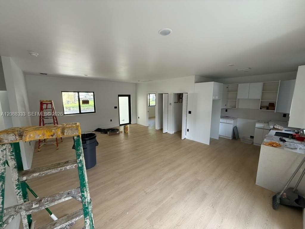 Open-concept interior featuring wood-finish flooring, recessed lighting, white cabinetry, and quartz countertops