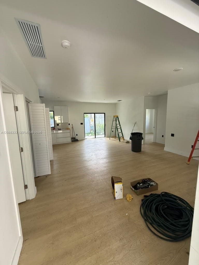 Open-concept interior featuring wood-finish flooring, recessed lighting, and a glass sliding door with access to an exterior area