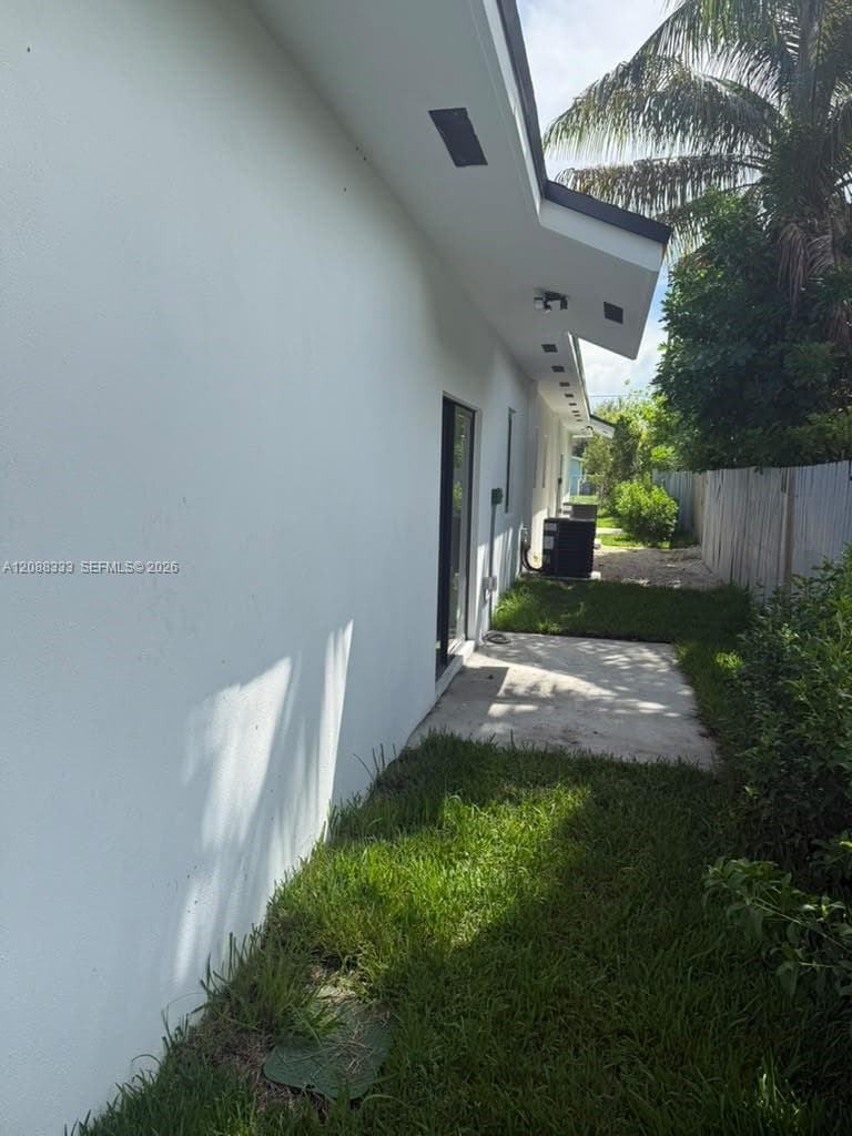 Stucco exterior finish with recessed soffit lighting, sliding glass door, concrete patio, and fenced yard area