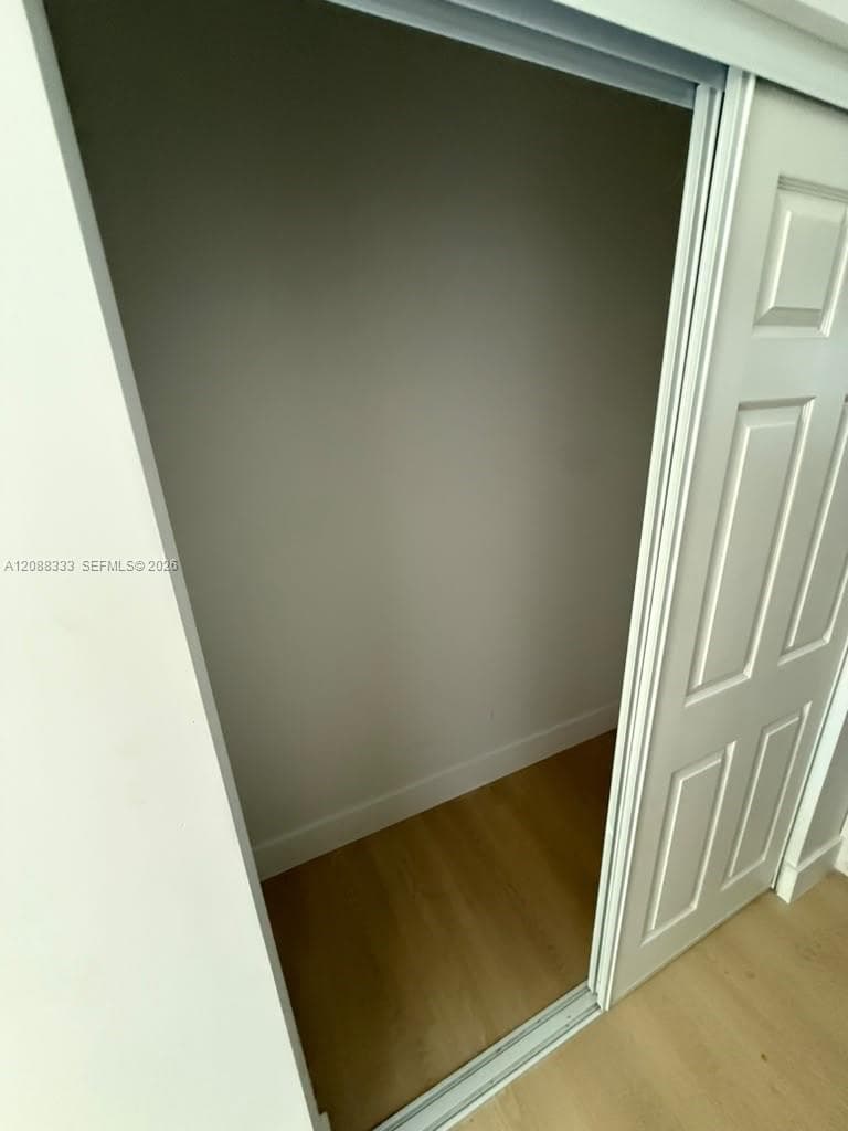 Storage area featuring a four-panel sliding door and wood-finish flooring