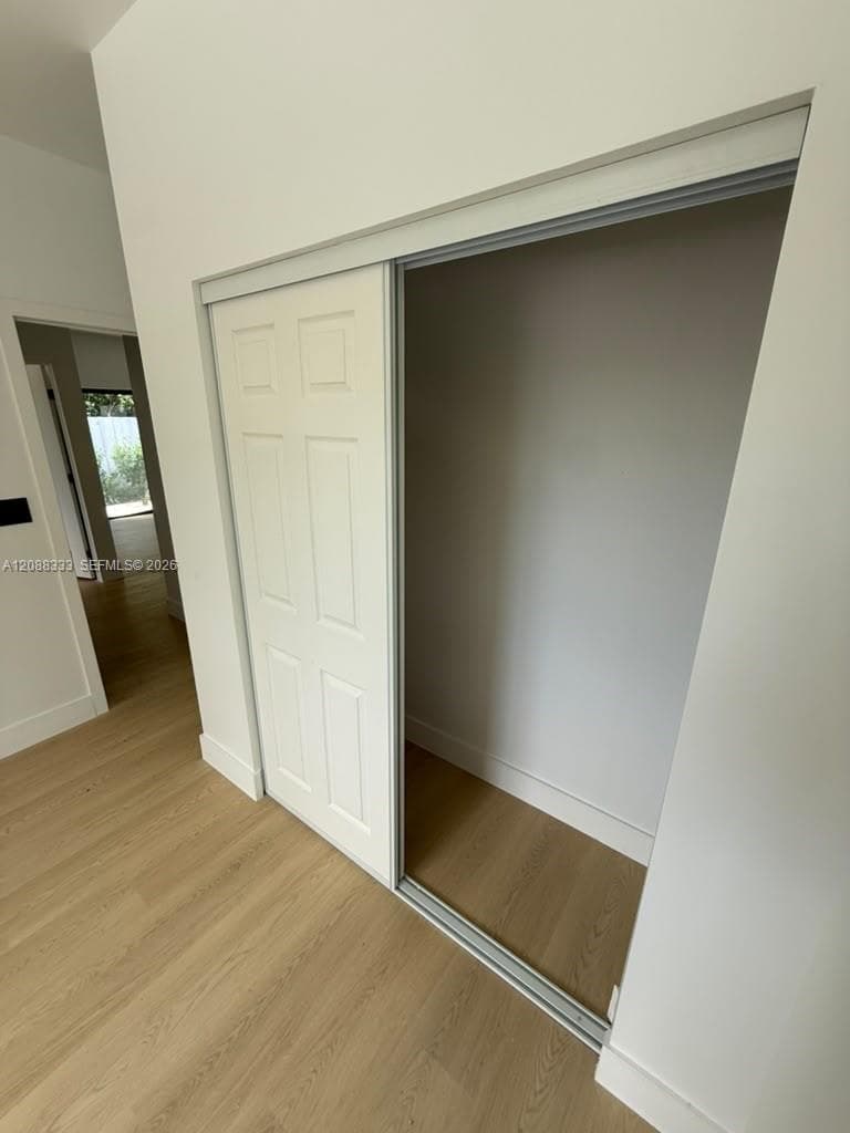 Closet featuring six-panel sliding door and wood-finish flooring