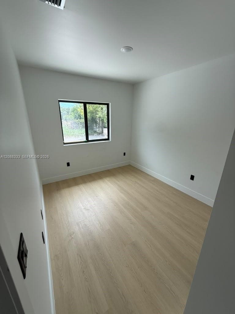 Room featuring wood-finish flooring, a single-pane window with a black frame, recessed lighting, and neutral wall tones