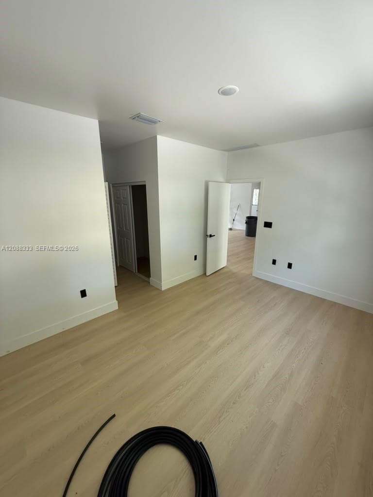 Neutral-toned wood-finish flooring, white walls, and interior doors with matte black hardware