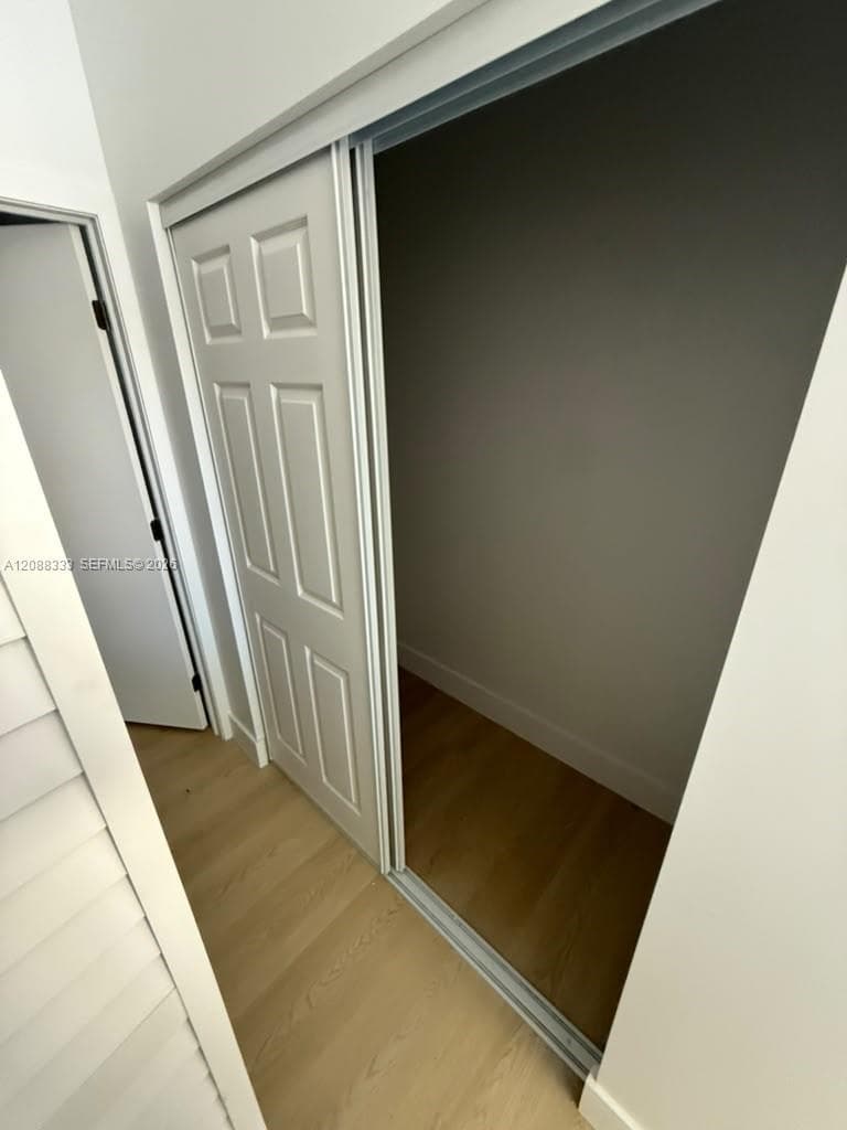 Storage area featuring six-panel sliding doors, wood-finish flooring, and crisp white trim