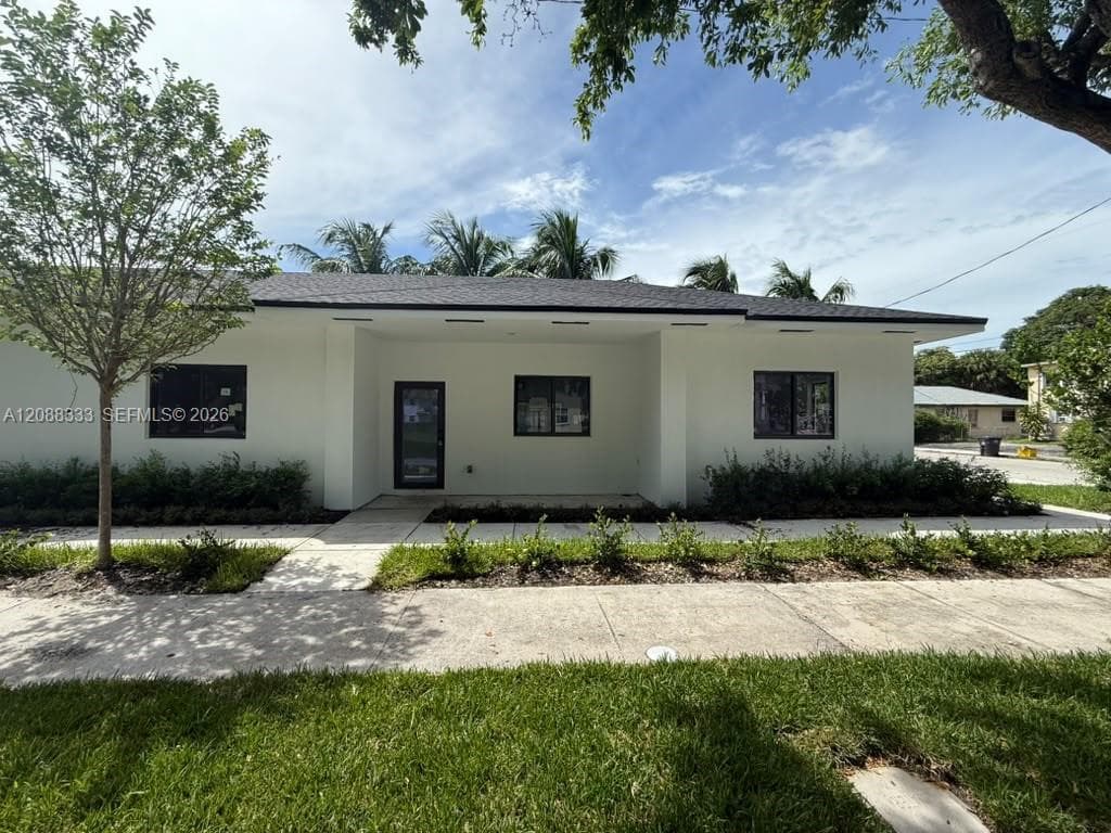 Single-story exterior featuring a smooth stucco facade, a recessed entryway, a dark-toned asphalt shingle roof, and dark-framed windows
