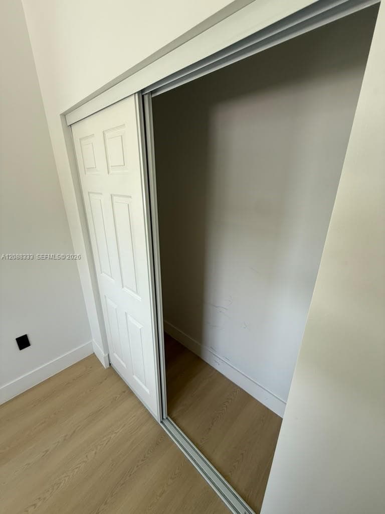 Sliding closet featuring six-panel doors and neutral wood-finish flooring