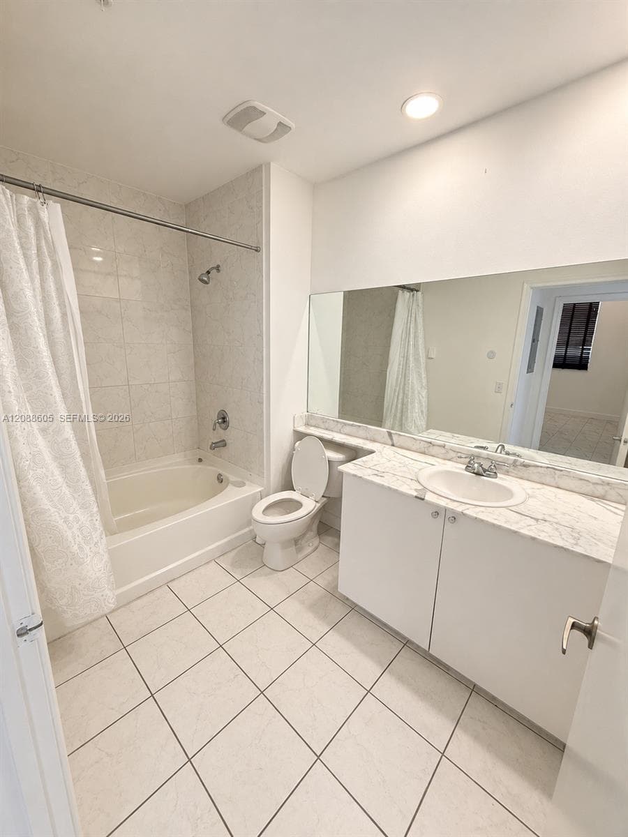 Bathroom featuring a vanity with an integrated basin, stone-finish countertop, full-width wall mirror, tile flooring, and a shower-tub combination with tile surround