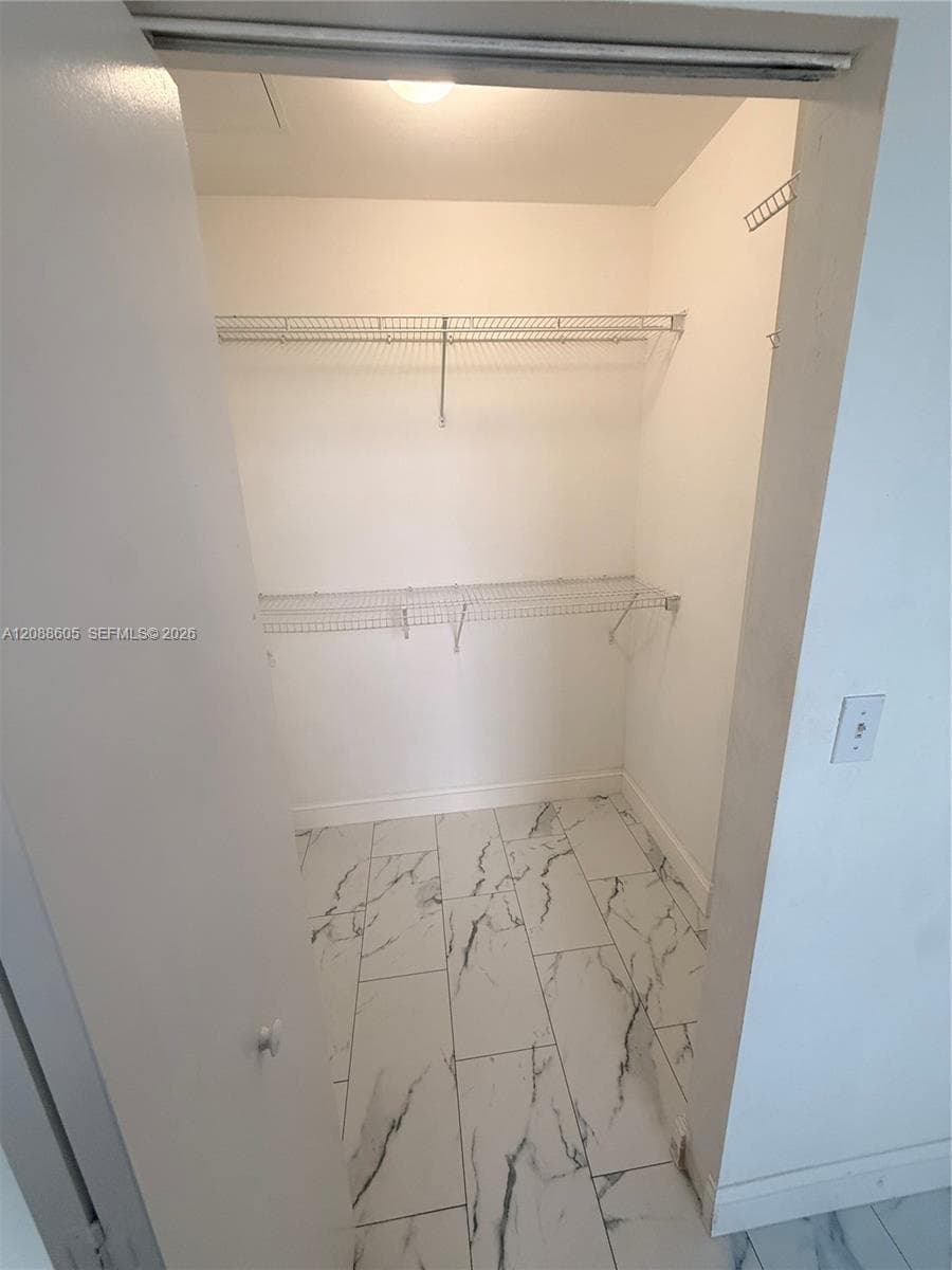 Reach-in closet featuring stone-patterned tile flooring and dual-tier wire shelving