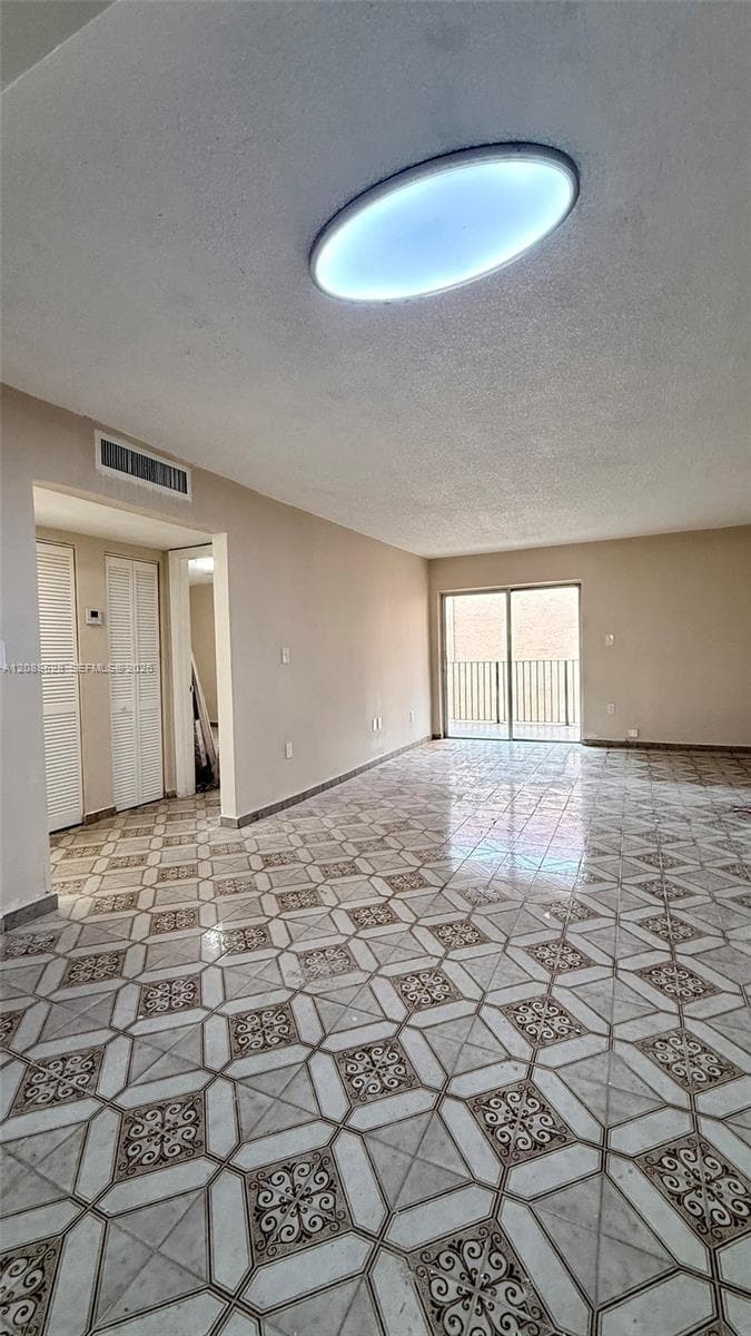 Geometric patterned tile flooring, oval flush-mount ceiling lighting, floor-to-ceiling sliding glass doors, and dual louvered closet doors