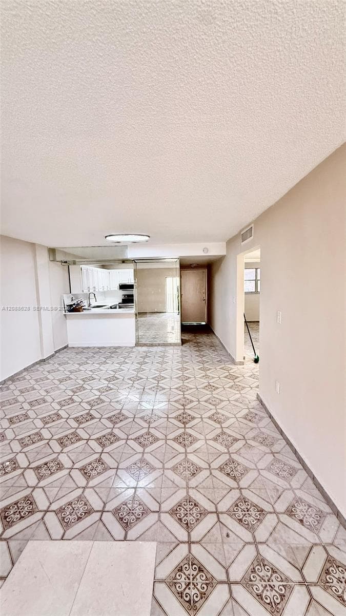 Patterned tile flooring, mirrored wall accent, and kitchen featuring a breakfast bar with white cabinetry