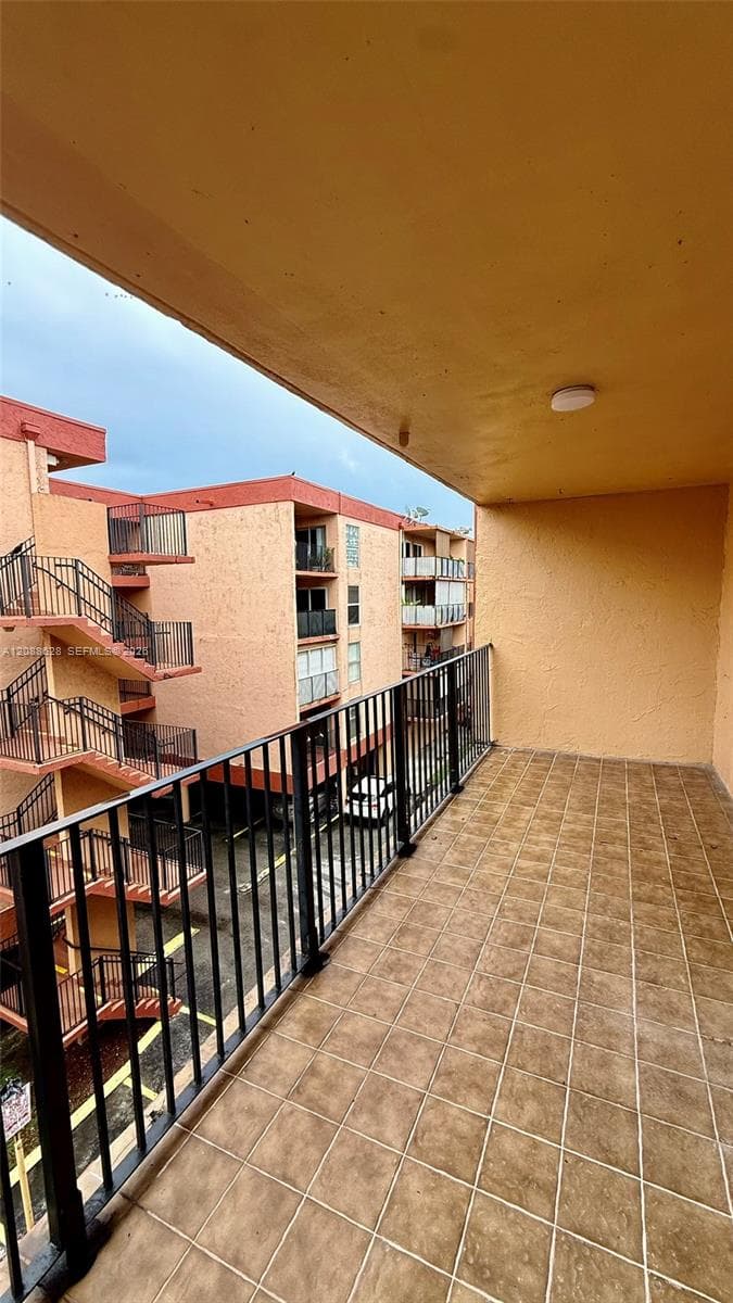Covered balcony featuring tile flooring, metal railings, and a ceiling-mounted light fixture
