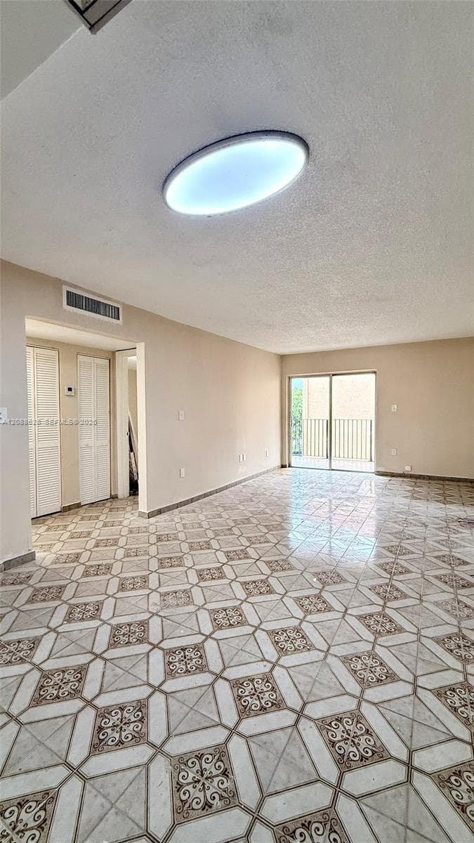 Interior space featuring decorative patterned tile flooring, an oval flush-mount ceiling light, sliding glass door, and louvered closet doors