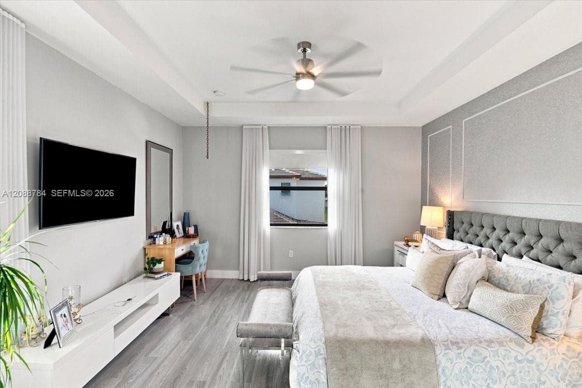 Tray ceiling with recessed lighting, wood-finish flooring, ceiling fan, and window with vertical blinds