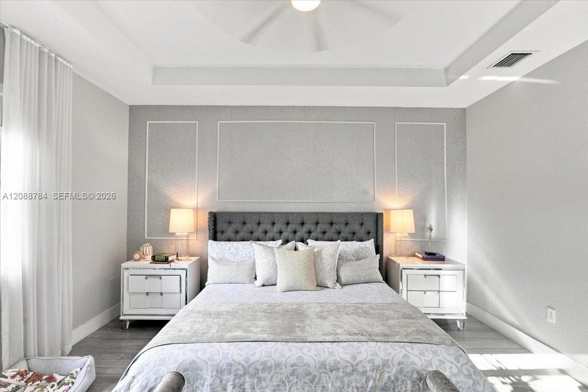 Tray ceiling with recessed lighting, textured accent wall, decorative wall molding, wood-finish flooring, and a ceiling fan