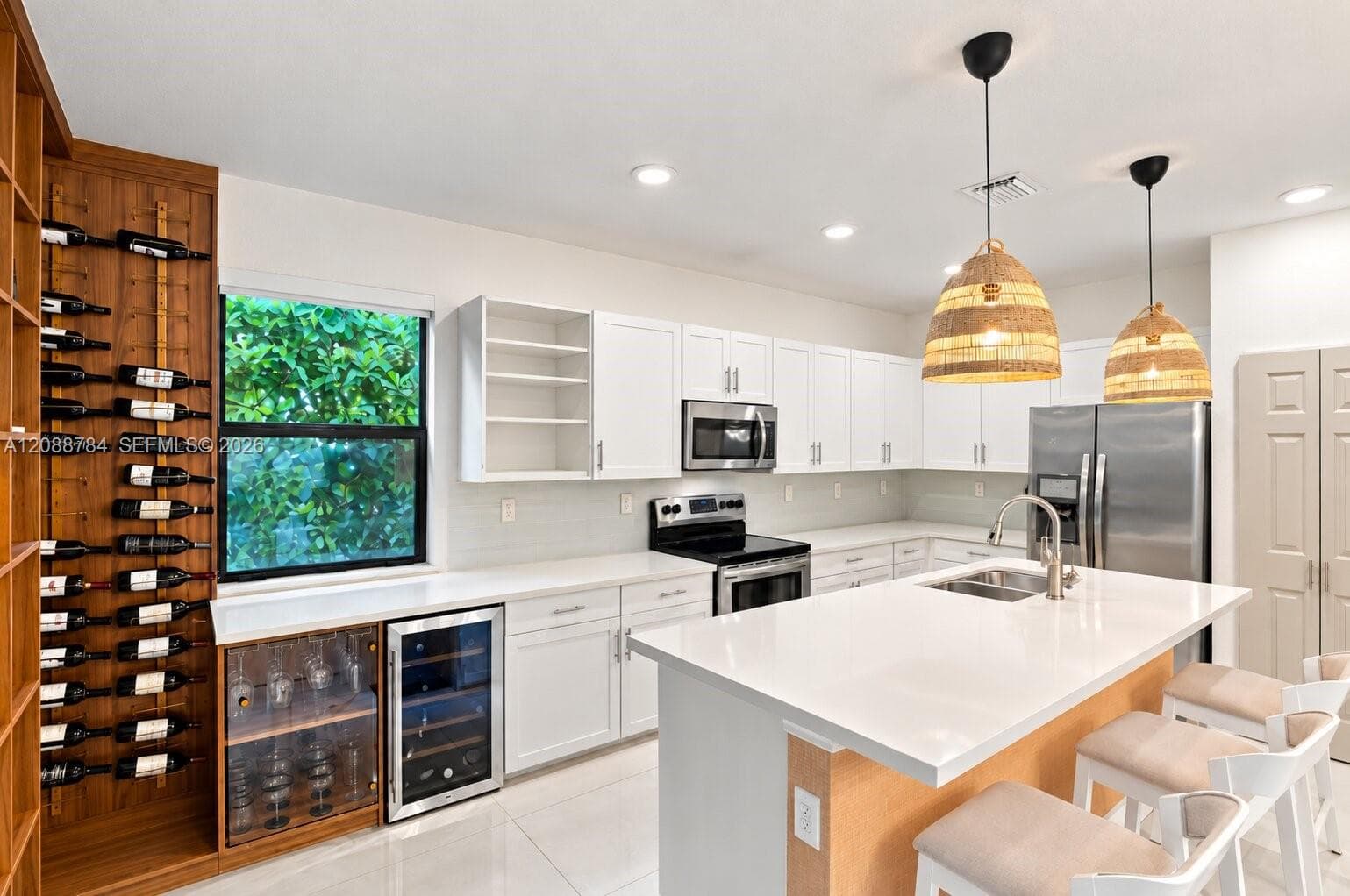 White shaker cabinetry with stainless steel appliances, a white island countertop, and a built-in wine rack