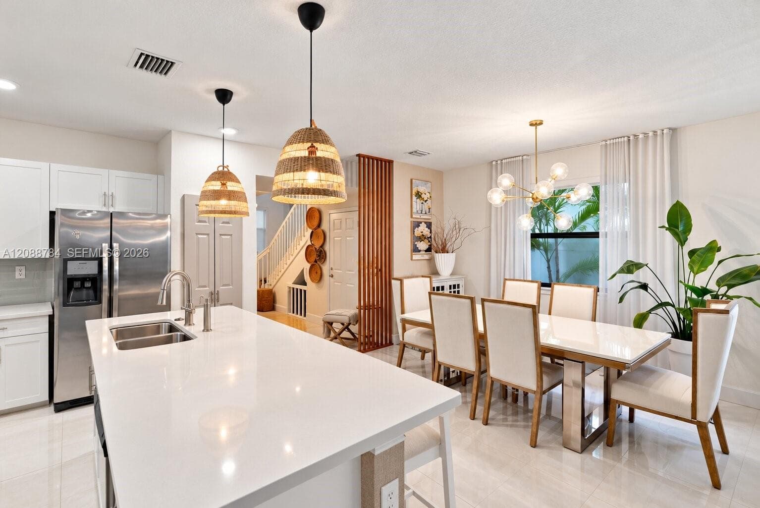 Kitchen featuring a white quartz island, stainless steel refrigerator, textured pendant lighting, and a slatted wood screen partition