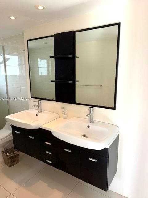 Floating double vanity with a stone countertop, integrated dual sinks, chrome faucets, and two framed wall-mounted mirrors featuring central shelving